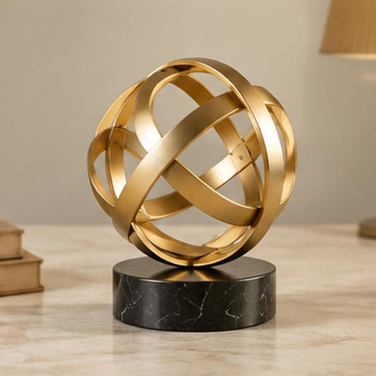 ESSENTIN Sculptural Gold Sphere with black marble base on a marble surface — modern elegance home decor